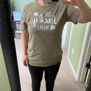 May include: A green t-shirt with white text that reads "One Lucky Mama" with a shamrock design.