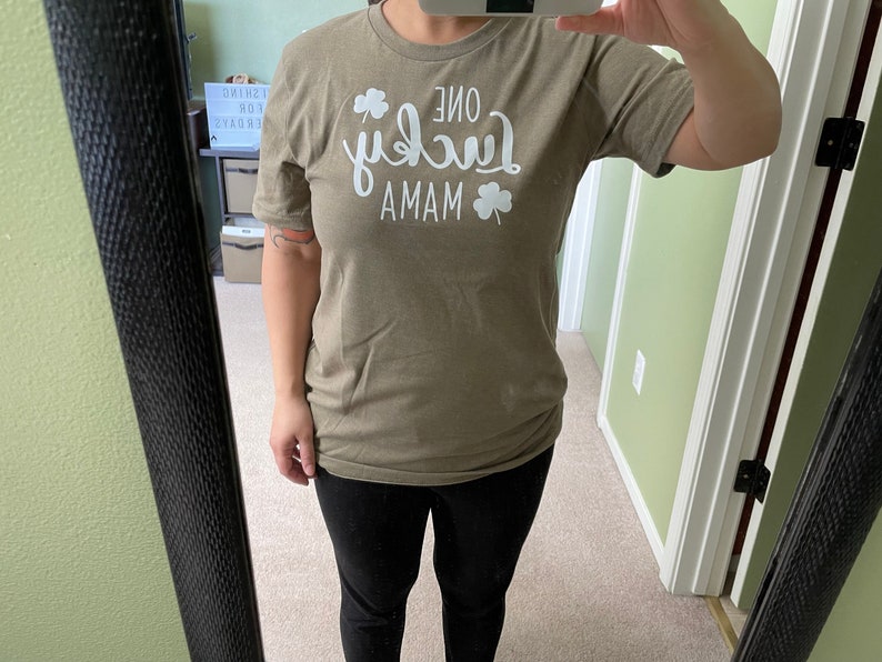 May include: A green t-shirt with white text that reads "One Lucky Mama" with a shamrock design.