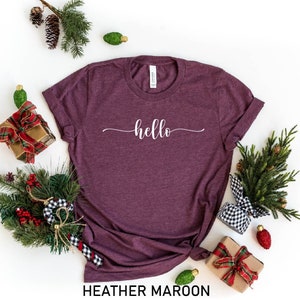 May include: A heather maroon t-shirt with the word "hello" written in white cursive script.