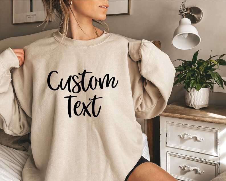 May include: A beige sweatshirt with the text "Custom Text" printed in black on the front.