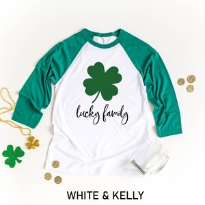 May include: White and green baseball tee shirt with a shamrock and the text "lucky family".