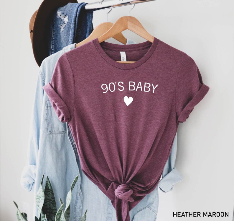 May include: Heather maroon t-shirt with the text "90's Baby" and a white heart.
