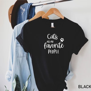 May include: Black t-shirt with white text that reads "Cats are my favorite people" and a white paw print.
