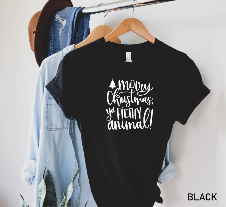 K&ouml;nnte beinhalten: Schwarzes T-Shirt mit wei&szlig;em Text, der "Frohe Weihnachten, du dreckiges Tier!" lautet.
