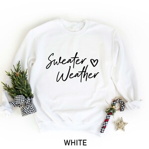 May include: White sweatshirt with the text "Sweater Weather" and a small heart symbol.
