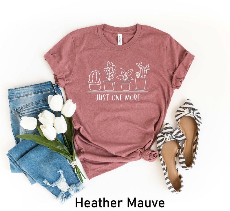 May include: Heather mauve t-shirt with a white graphic of potted plants and the text "Just One More".