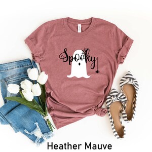 May include: Heather mauve t-shirt with a white ghost graphic and the text "Spooky" in black. The ghost has a spider web on its head and a spider hanging from a web.