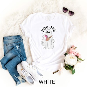 May include: White t-shirt with a ghost holding a pink drink and the text "BOO-JEE" printed on it.