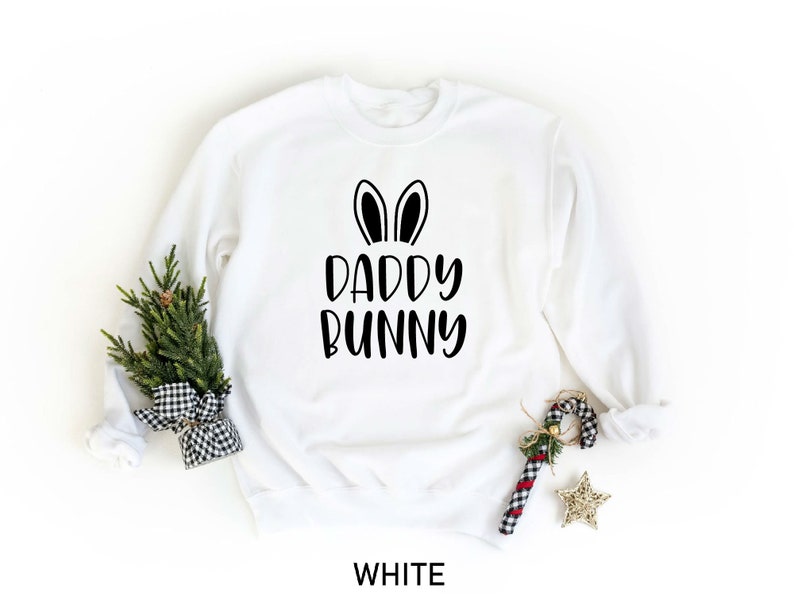 K&ouml;nnte beinhalten: Wei&szlig;er Pullover mit schwarzen Hasenohren und dem Aufdruck "Daddy Bunny" auf der Vorderseite.
