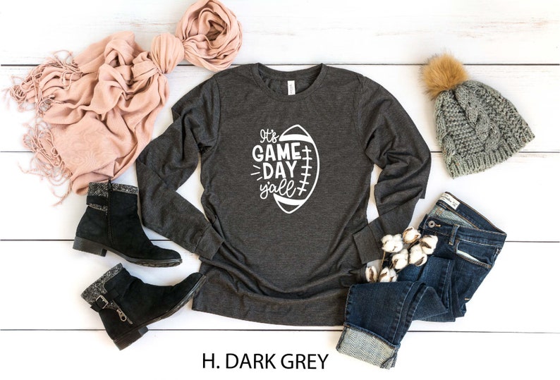 K&ouml;nnte beinhalten: Ein dunkelgraues Langarmshirt mit einer wei&szlig;en Grafik eines Fu&szlig;balls und dem Text "It's Game Day Y'all".