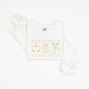 Featuring captivating tarot card graphics, this Astrology Tarot Card Graphic Tee is a must-have for fans of celestial zodiac symbolism.