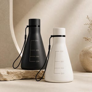 May include: A matte black water bottle and a matte white water bottle, both featuring a conical shape, a screw-top lid, a black carrying strap, and printed measurement markings ranging from 200 to 500 milliliters on the exterior surface.