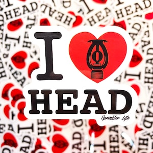 May include: A white sticker with a red heart and the text "I love HEAD" in black. The heart has a black sprinkler head inside. The text "Sprinkler Life" is in black at the bottom of the sticker.