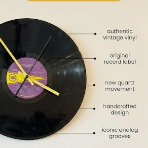 May include: A black vinyl record clock with yellow and black clock hands. The clock features an original record label and the text "Time for a Classic". The clock is a handcrafted design with a new quartz movement.