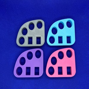 May include: Four different colored plastic ring sizers, each with five round holes and three rectangular slots. The sizers are gray, blue, purple, and pink.