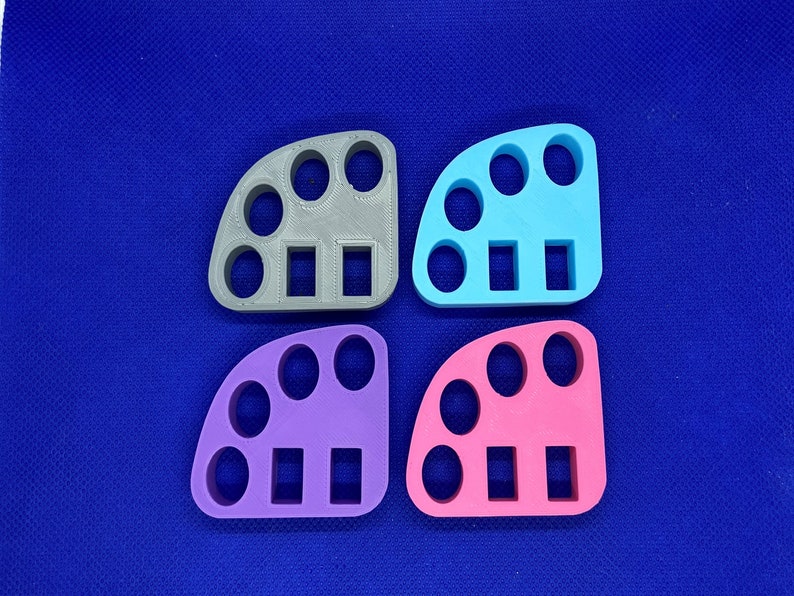 May include: Four different colored plastic ring sizers, each with five round holes and three rectangular slots. The sizers are gray, blue, purple, and pink.