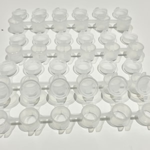 May include: A white plastic tray with 42 small, round, clear containers. The containers are arranged in a grid pattern.