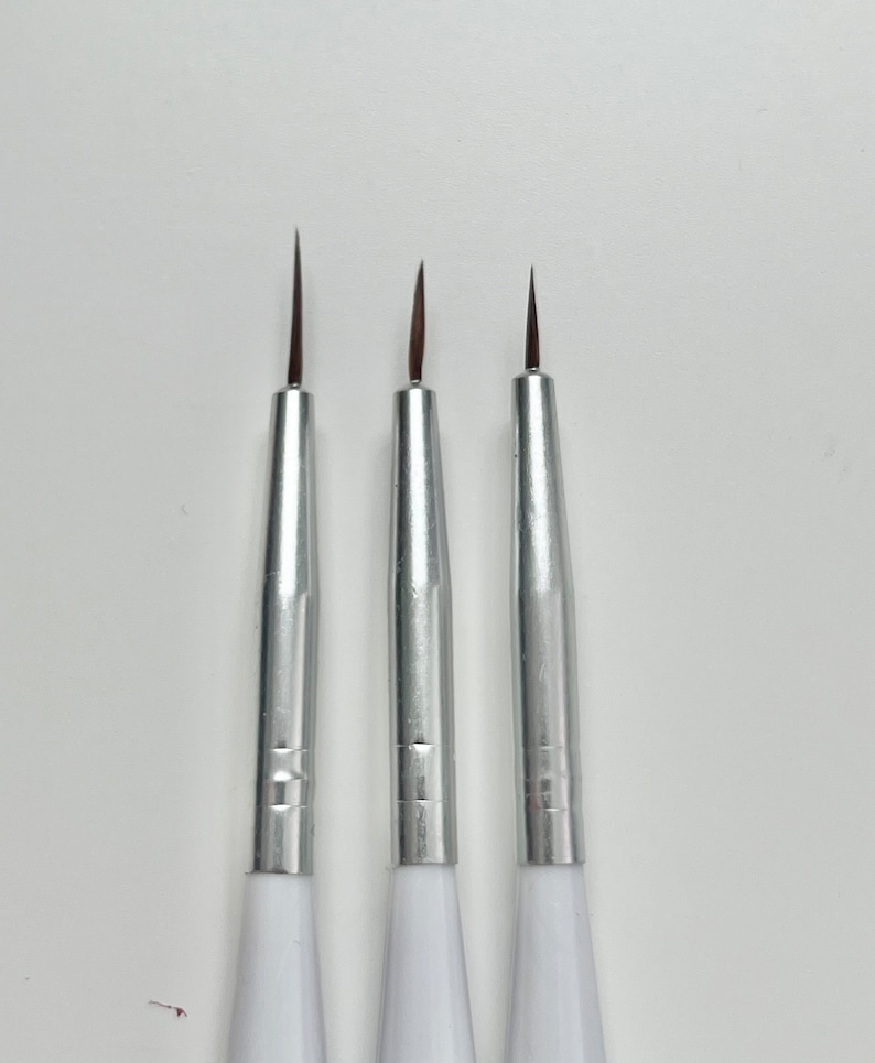 May include: Three silver and white detail paint brushes with fine tips.