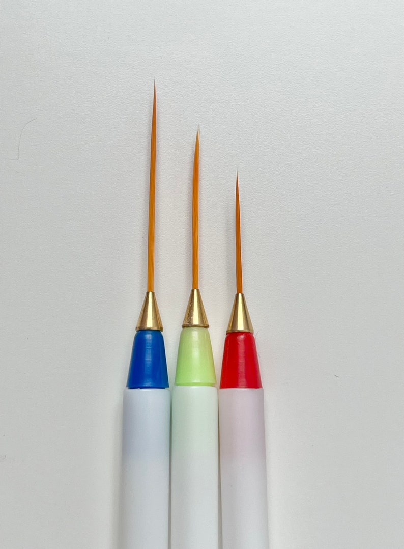 May include: Three paint brushes with different colored handles: blue, green, and red. The brushes have fine tips and are ideal for detail work.