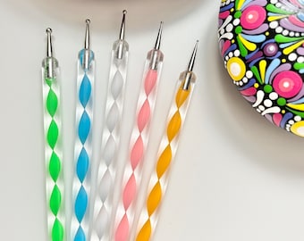 Può includere: Set di sei strumenti per punteggiare per la pittura su roccia. Gli strumenti hanno manici in plastica trasparente con un motivo a spirale in verde, blu, bianco, rosa e giallo. Ogni strumento ha una piccola sfera metallica all'estremità.
