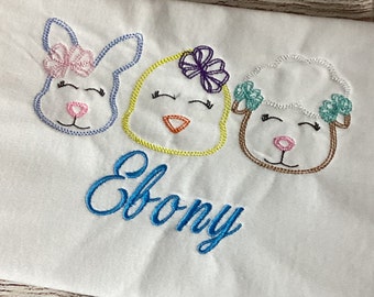 May include: White embroidered baby onesie with a bunny, chick, and lamb design. The onesie has the name "Ebony" embroidered in blue.