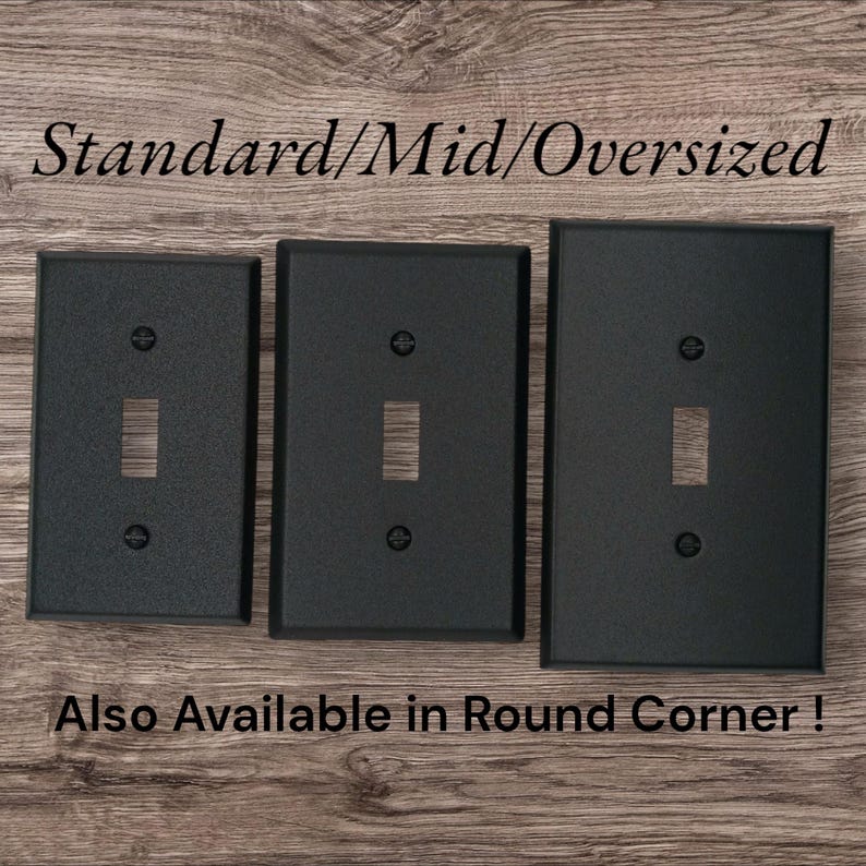 Three black metal toggle switch plates next to each other on a brown wood background. The words" Standard/Mid/Oversized" are shown above the plates, and "Also available in round corner" is written below the plates.