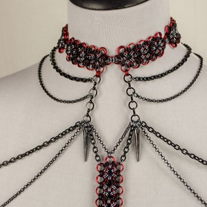 May include: A red and black chainmail choker necklace with multiple black chain strands and spikes hanging from the bottom.