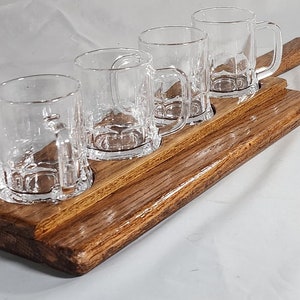 May include: A wooden serving tray with four clear glass mugs with handles. The tray is brown and has a natural wood grain.