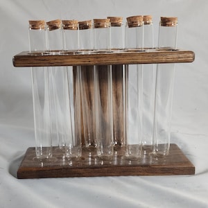 May include: A wooden stand with ten clear glass test tubes. The stand is dark brown wood with a natural wood grain. The test tubes are all the same size and are arranged in a row.