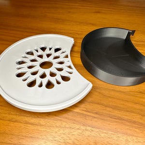 Könnte beinhalten: Ein weißes, halbrundes Tablett mit einem dekorativen, lasergeschnittenen Design. Das Tablett wird mit einem schwarzen, halbrunden Tablett geliefert.