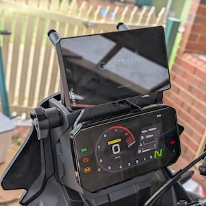 Może przedstawiać: Czarny kokpit motocykla z zamontowanym na górze systemem nawigacji GPS Garmin. Kokpit wyświetla cyfrowy prędkościomierz, obrotomierz i inne informacje, w tym aktualny odczyt licznika kilometrów 1066 km.