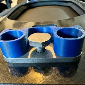 May include: A 3D printed blue plastic cup holder with a gray metal base and a threaded screw. The cup holder has two cups and is designed to be mounted on a surface.