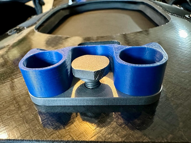 May include: A 3D printed blue plastic cup holder with a gray metal base and a threaded screw. The cup holder has two cups and is designed to be mounted on a surface.