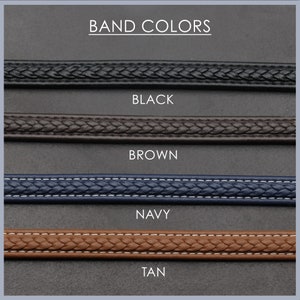 May include: Four different coloured watch bands: black, brown, navy, and tan. The bands are all braided and have a stitched edge.