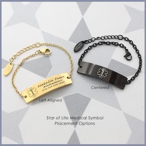 May include: Two medical alert bracelets, one gold and one black, with a star of life symbol and personalized text. The gold bracelet has the text "Natalie Peers Alzheimers ICE:123.456.7890" and the black bracelet has the star of life symbol centered on the tag. The text on the gold bracelet is left aligned.
