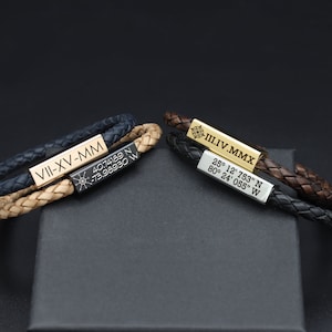 May include: Two leather bracelets with engraved metal plates. The top bracelet is brown and black with a gold plate that reads "III.IV.MMX" and "25° 12' 753" N 80° 24' 055" W". The bottom bracelet is tan and black with a black plate that reads "VII-XV-MM" and "40.74189 N -73.98930 W".