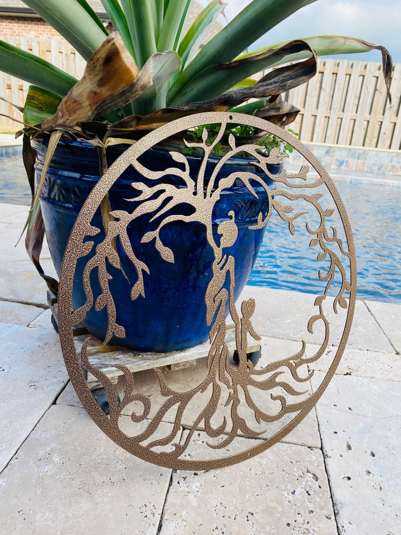 May include: A bronze metal wall art piece depicting a tree of life with intricate branches and roots. The tree is surrounded by a circular frame.