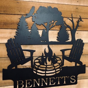 May include: Black metal silhouette of a campfire scene with two chairs, a fire pit, and trees. The name "BENNETT'S" is written below the scene.
