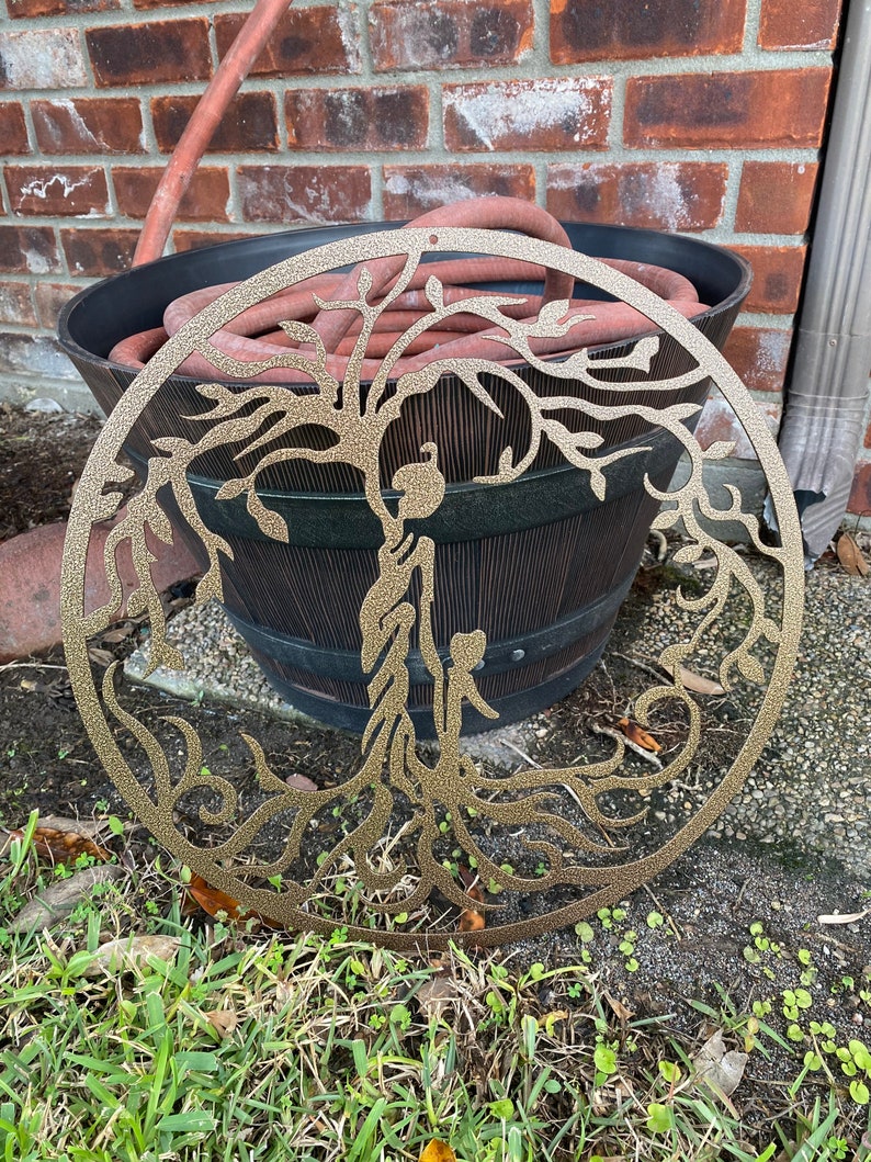 May include: A gold metal tree of life wall decor with intricate branches and roots. The design is cut out of the metal, creating a delicate and airy look.