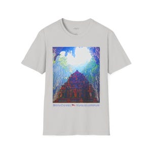 May include: A light gray t-shirt featuring a colorful image of a temple with a vibrant sky and lush greenery. The text "Batu Caves Kuala Lumpur" is printed at the bottom of the image. The shirt is made of a soft material.