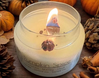 May include: A clear glass jar candle with a white wax base and a lit wick. The candle is labeled "Pumpkin Spice" with the ingredients listed below: Cinnamon, Nutmeg, Clove, Coconut Wax, Essential Oils.