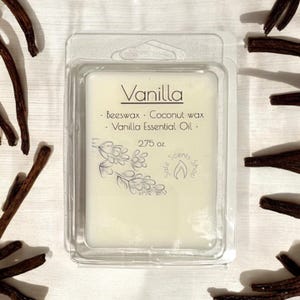 May include: A white wax melt in a clear plastic container. The wax melt is labeled "Vanilla" and lists the ingredients as beeswax, coconut wax, and vanilla essential oil. The wax melt is 2.75 ounces.