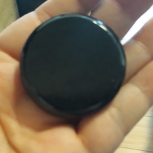 Può includere: Un disco rotondo nero con una superficie liscia e lucida.