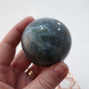 May include: A smooth, polished sphere of grey and white agate with a swirling pattern. The sphere is approximately 5 cm in diameter.