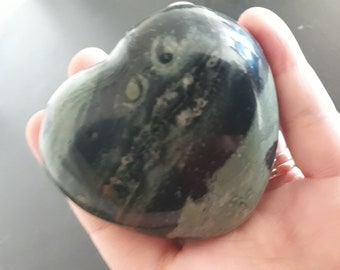 Puede incluir: Una piedra verde y negra en forma de corazón con patrones de remolino.