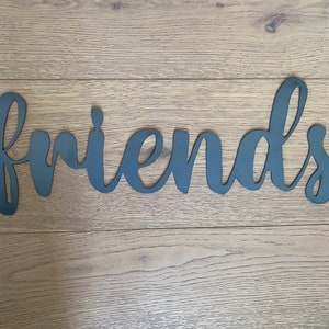 May include: Black metal wall decor with the word "friends" in a cursive font.