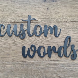 May include: Black metal words "custom words" on a wooden background.