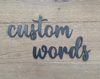 May include: Black metal words "custom words" on a wood background.
