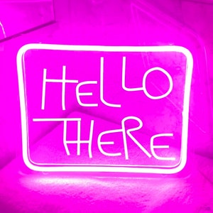 Może przedstawiać: Neonowy znak z białą ramką i białymi neonowymi literami, na którym widnieje napis "HELLO THERE" na różowym tle.