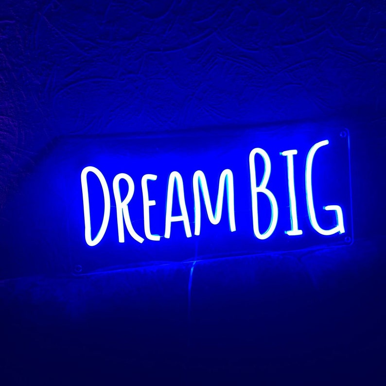 K&ouml;nnte beinhalten: Ein blaues Neon-Schild mit den Worten "DREAM BIG" in Wei&szlig;.